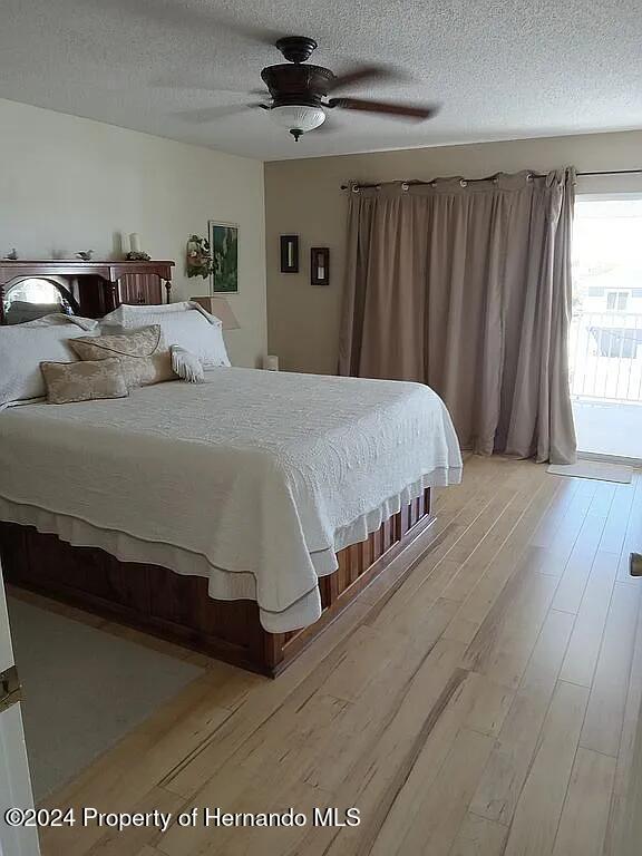 bedroom featuring ceiling fan, a textured ceiling, access to exterior, and light hardwood / wood-style flooring