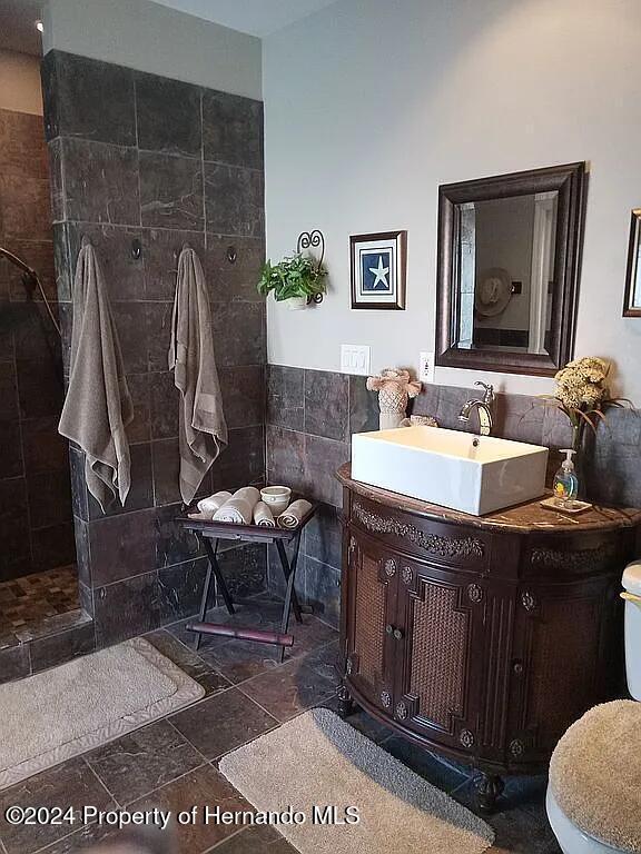 bathroom featuring toilet, vanity, and tile walls