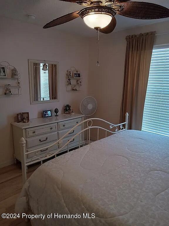 bedroom with multiple windows, wood-type flooring, and ceiling fan