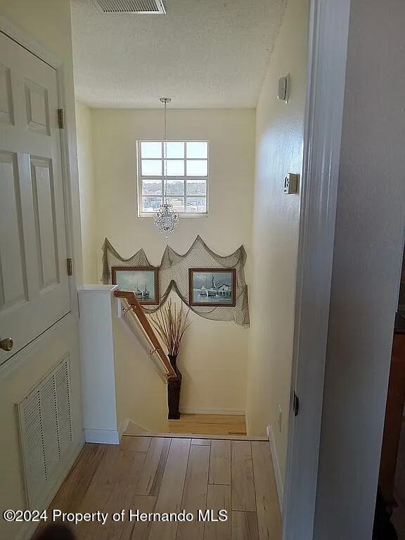 interior space featuring an inviting chandelier, a textured ceiling, and hardwood / wood-style flooring