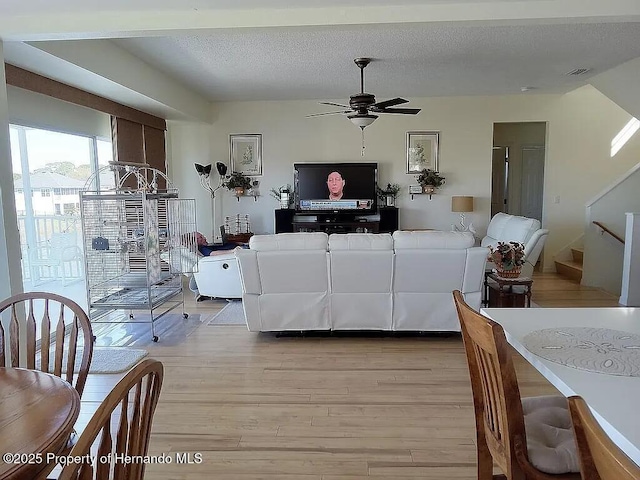 3519 Cobia Dr, Hernando Beach, FL 34607 - living room with light wood finished floors, ceiling fan, a textured ceiling, and stairway