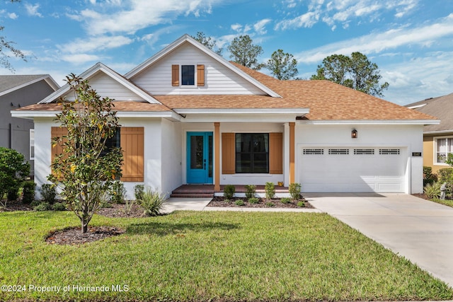 view of front of home with a garage, a front yard, and a porch