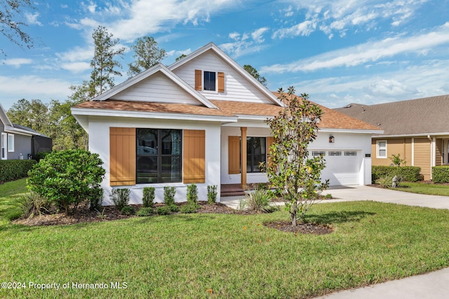 view of front of property featuring covered porch, a garage, and a front lawn