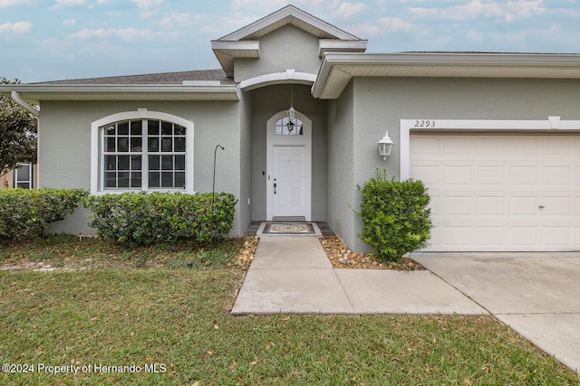 entrance to property featuring a garage and a yard