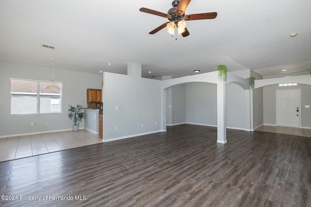 unfurnished living room featuring dark wood-type flooring and ceiling fan