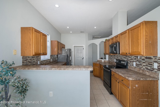 kitchen with light tile patterned flooring, kitchen peninsula, stainless steel fridge, black / electric stove, and decorative backsplash