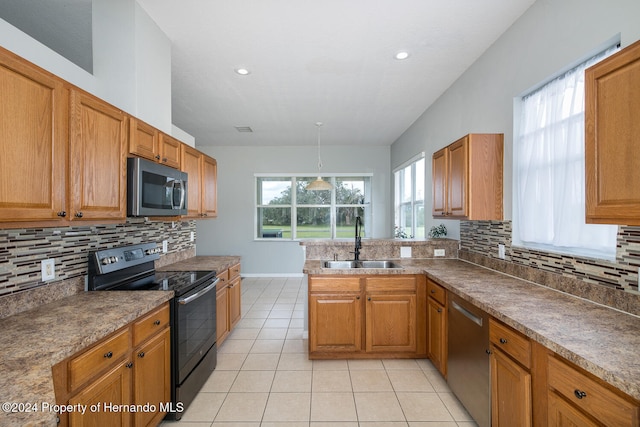 kitchen with a wealth of natural light, sink, decorative backsplash, and appliances with stainless steel finishes