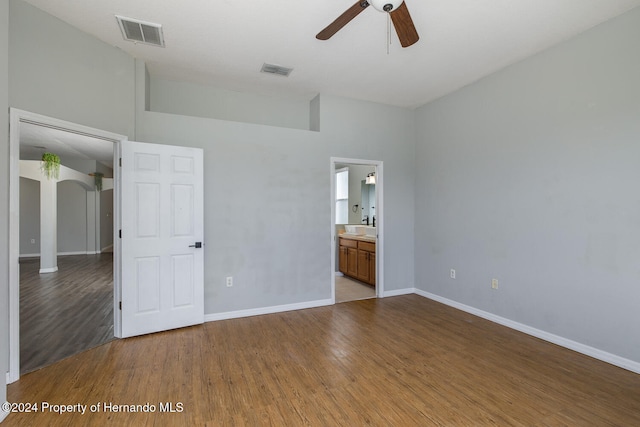 unfurnished bedroom with a towering ceiling, ceiling fan, connected bathroom, and light hardwood / wood-style flooring