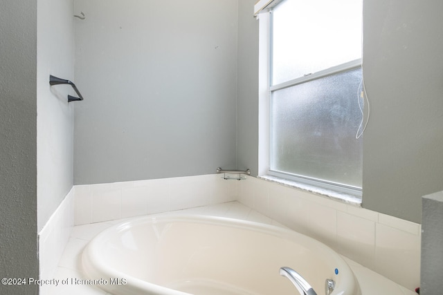 bathroom featuring a wealth of natural light and a relaxing tiled tub