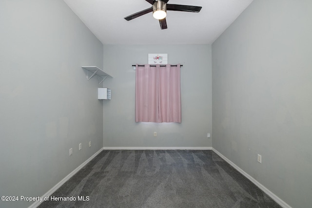 spare room featuring dark colored carpet and ceiling fan