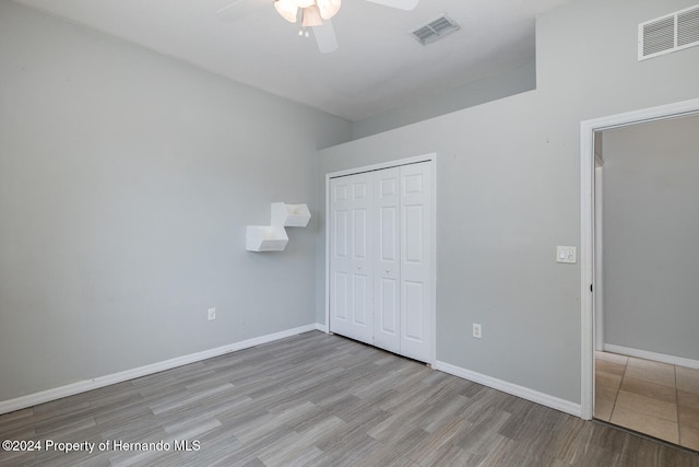 unfurnished bedroom featuring ceiling fan, a closet, and light wood-type flooring