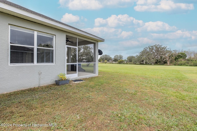 view of yard featuring ceiling fan and a sunroom