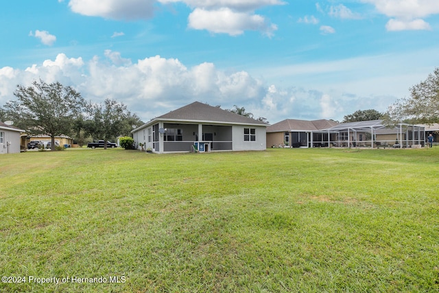 rear view of house featuring a sunroom, a lawn, and a lanai