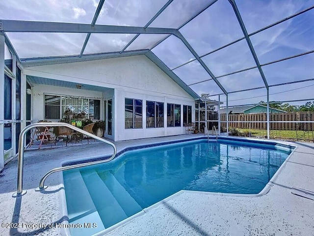 view of swimming pool with glass enclosure and a patio