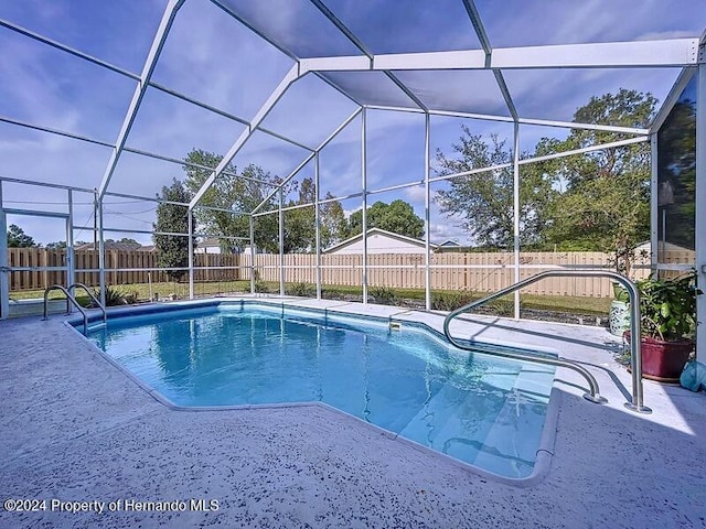 view of swimming pool featuring glass enclosure and a patio area