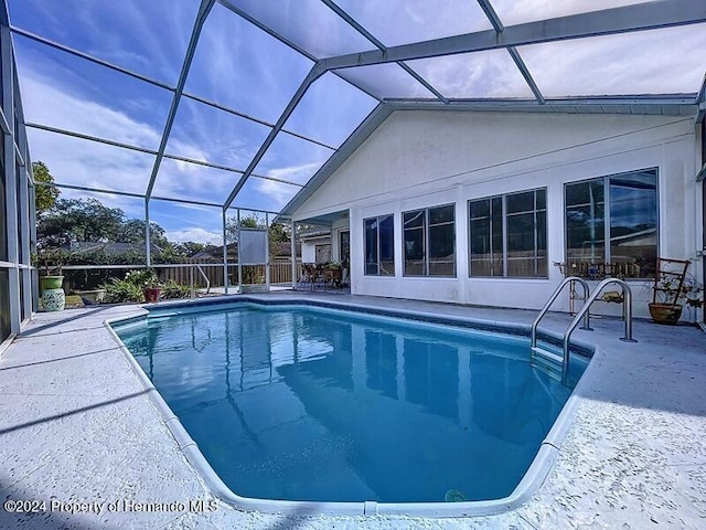 view of swimming pool featuring a lanai and a patio area