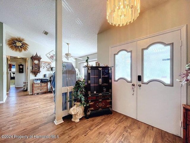 entryway featuring hardwood / wood-style flooring, ceiling fan with notable chandelier, a textured ceiling, lofted ceiling, and french doors