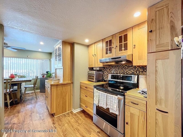 kitchen featuring light hardwood / wood-style floors, light brown cabinetry, backsplash, stainless steel electric range oven, and range hood