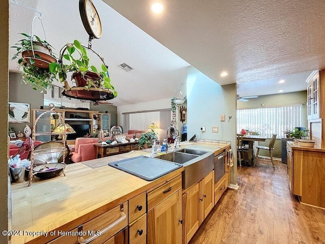 kitchen with light hardwood / wood-style floors, sink, wooden counters, ceiling fan, and a textured ceiling