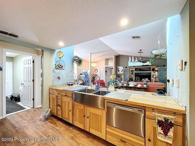 kitchen with vaulted ceiling, a textured ceiling, sink, ceiling fan, and light wood-type flooring