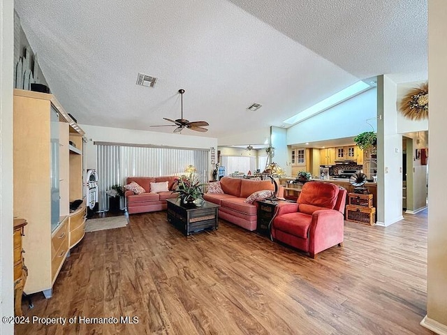 living room featuring a textured ceiling, hardwood / wood-style flooring, a skylight, and ceiling fan