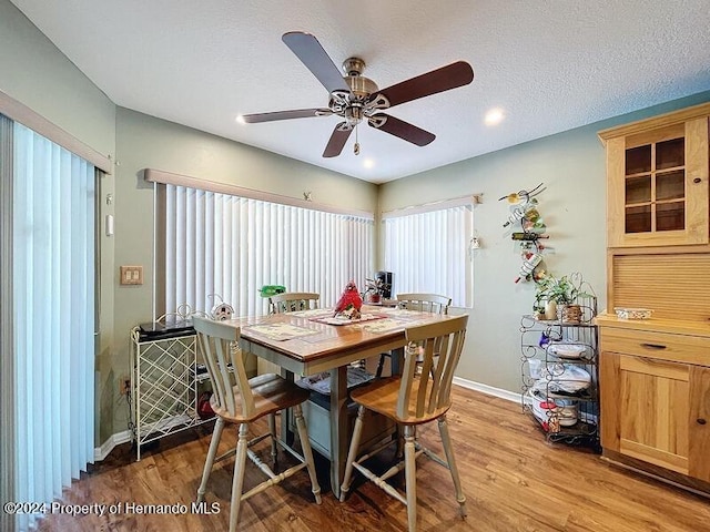 dining area with light hardwood / wood-style floors, ceiling fan, and a textured ceiling