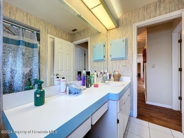 bathroom featuring walk in shower, vanity, a textured ceiling, and tile patterned floors