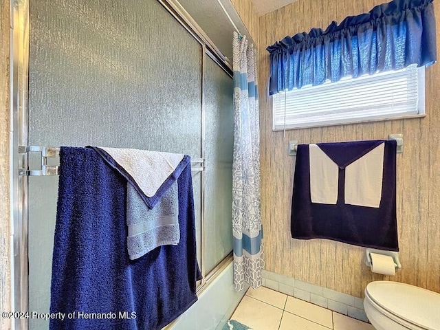 bathroom with toilet, wooden walls, tile patterned floors, and enclosed tub / shower combo