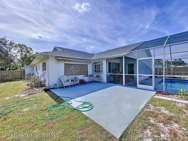 rear view of property featuring a lawn, a lanai, a fenced in pool, and a patio area