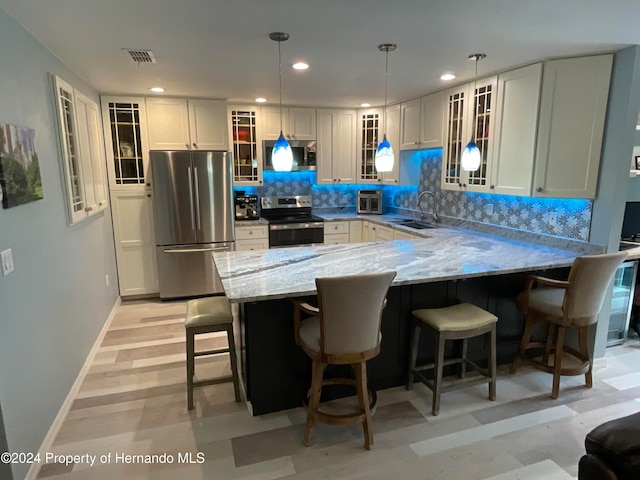 kitchen featuring sink, light stone counters, appliances with stainless steel finishes, backsplash, and pendant lighting