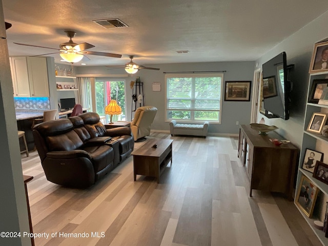 living room with light wood-type flooring, built in desk, and ceiling fan