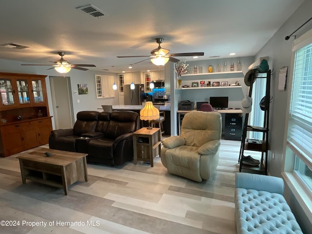 living room featuring radiator, ceiling fan, built in desk, and light hardwood / wood-style floors