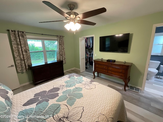 bedroom with ceiling fan, a spacious closet, connected bathroom, a closet, and light wood-type flooring