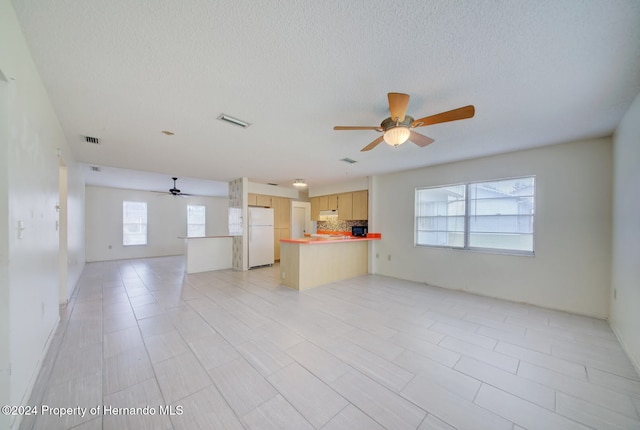 unfurnished living room with ceiling fan and a textured ceiling