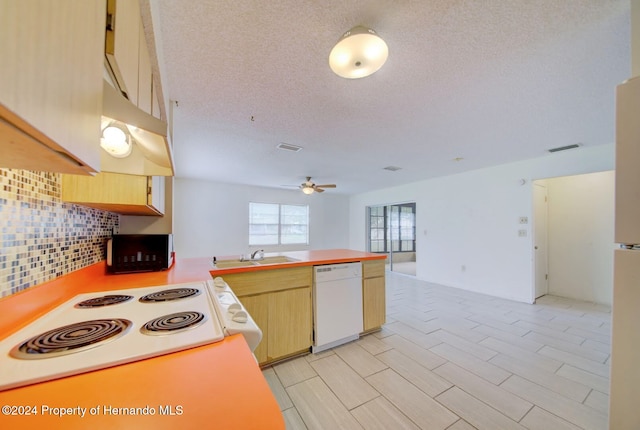 kitchen featuring white appliances, sink, decorative backsplash, ceiling fan, and kitchen peninsula