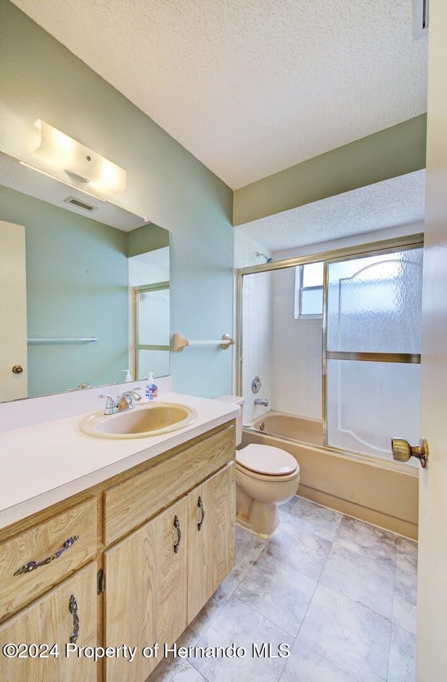 full bathroom featuring vanity, tile patterned flooring, toilet, enclosed tub / shower combo, and a textured ceiling