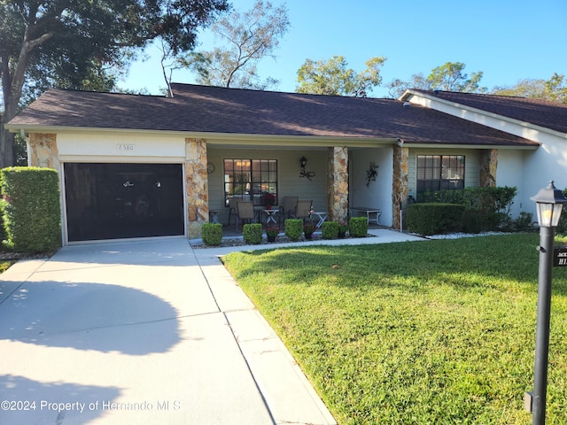 single story home featuring a front yard, a porch, and a garage