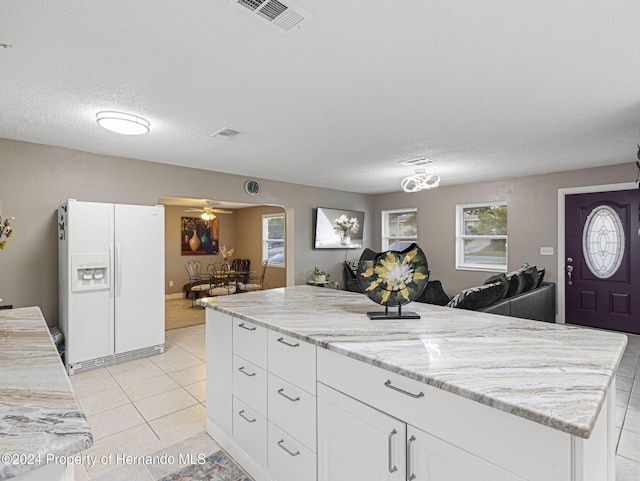 1009 Cobbelstone Dr, Spring Hill, FL 34606 - kitchen featuring white fridge with ice dispenser, light tile patterned floors, a textured ceiling, white cabinetry, and a ceiling fan