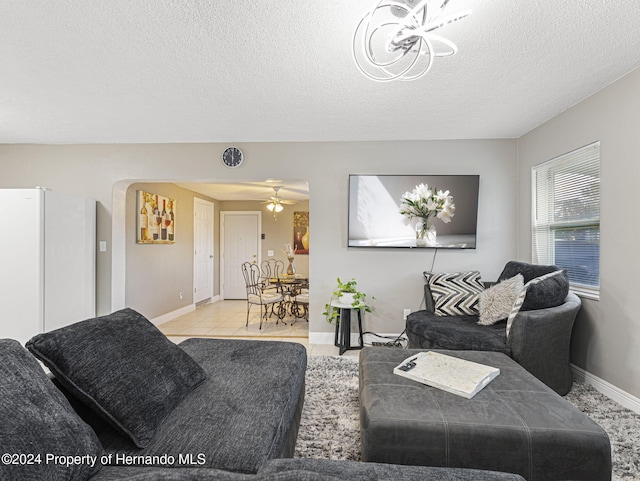 living room with a textured ceiling, light tile patterned floors, and ceiling fan