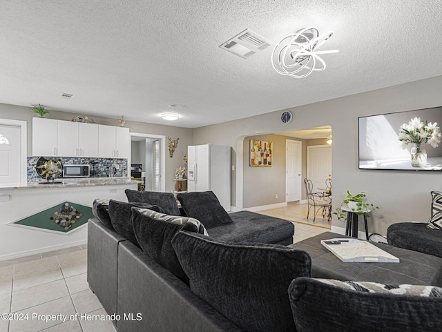 tiled living room featuring a textured ceiling