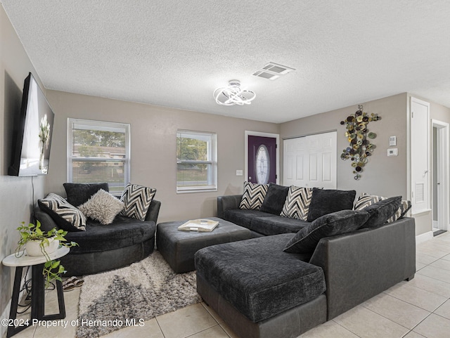 living room featuring a textured ceiling, light tile patterned floors, and a healthy amount of sunlight