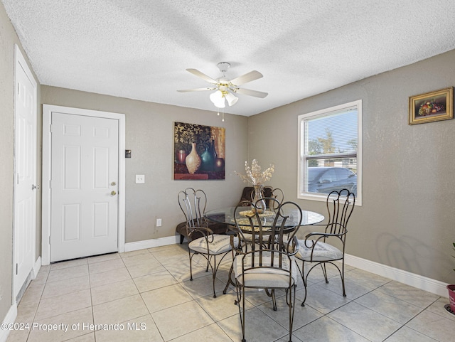 tiled dining space with ceiling fan and a textured ceiling