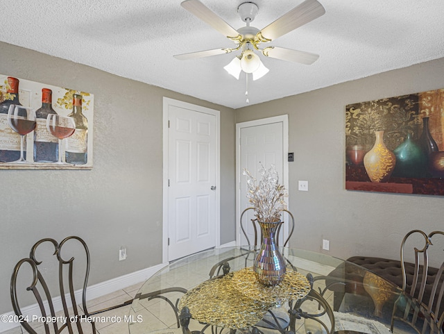 tiled dining space featuring a textured ceiling and ceiling fan