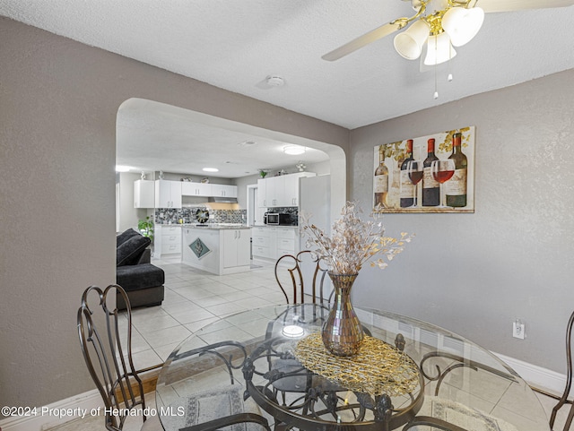 dining space with a textured ceiling, ceiling fan, and light tile patterned floors