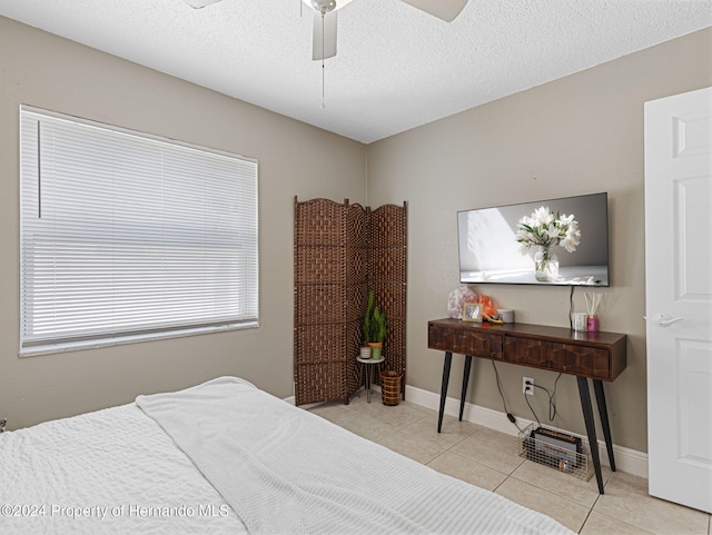 bedroom with ceiling fan, a textured ceiling, and light tile patterned floors