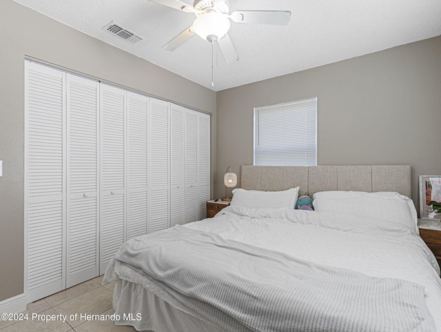 tiled bedroom featuring ceiling fan, a textured ceiling, and a closet