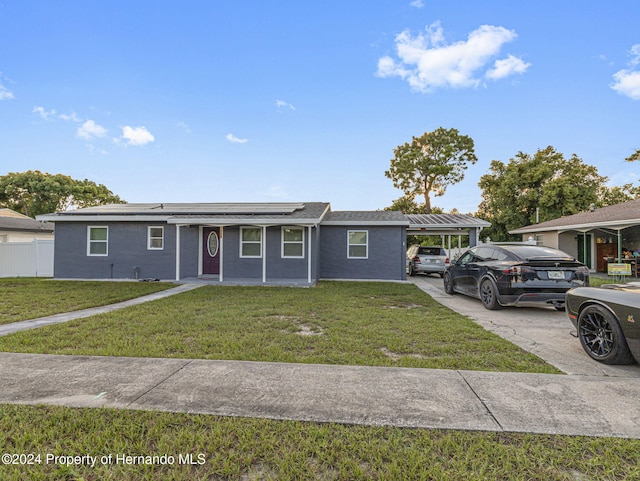 view of front of house featuring a front yard, solar panels, and a carport