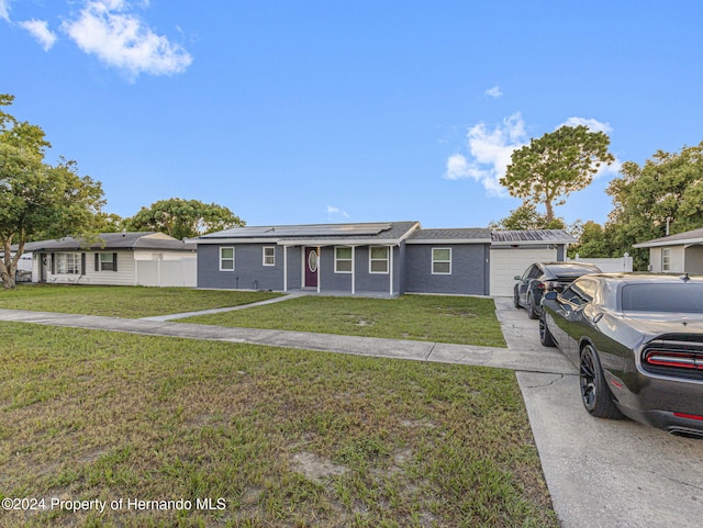 ranch-style house with solar panels, a front yard, and a garage