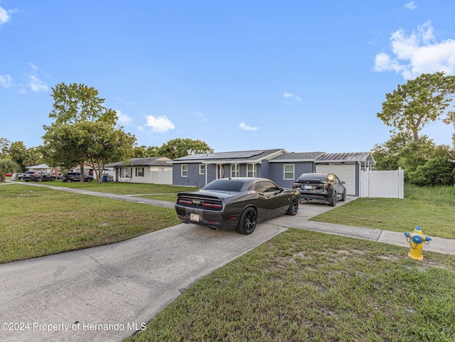 1009 Cobbelstone Dr, Spring Hill, FL 34606 - single story home with concrete driveway, an attached garage, a front lawn, roof mounted solar panels, and a residential view