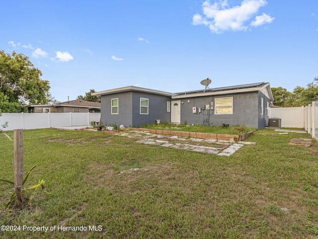 1009 Cobbelstone Dr, Spring Hill, FL 34606 - back of property featuring solar panels, cooling unit, and stucco siding
